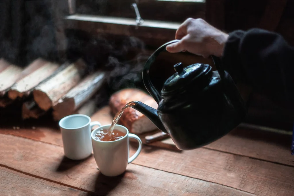 Someone pours tea in a white cup.